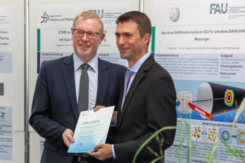 Prof. Dr. Fink und Stefan Müller, Parlamentarischer Staatssekretär bei der Bundesministerin für Bildung und Forschung, bei der Bescheidübergabe (Foto: Matthias Weißer, FAU)