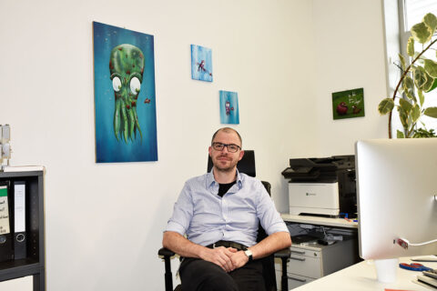 Das Bild zeigt Dr. Alexander Scherer an seinem Schreibtisch im Büro.